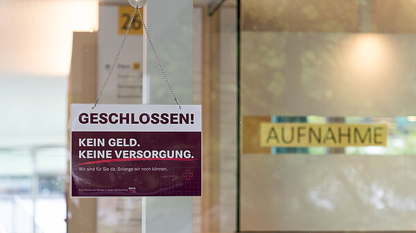 An einer Tür hängt ein Geschlossen-Schild. Im Hintergrund ist verschwommen das Schild "Aufnahme" zu sehen.