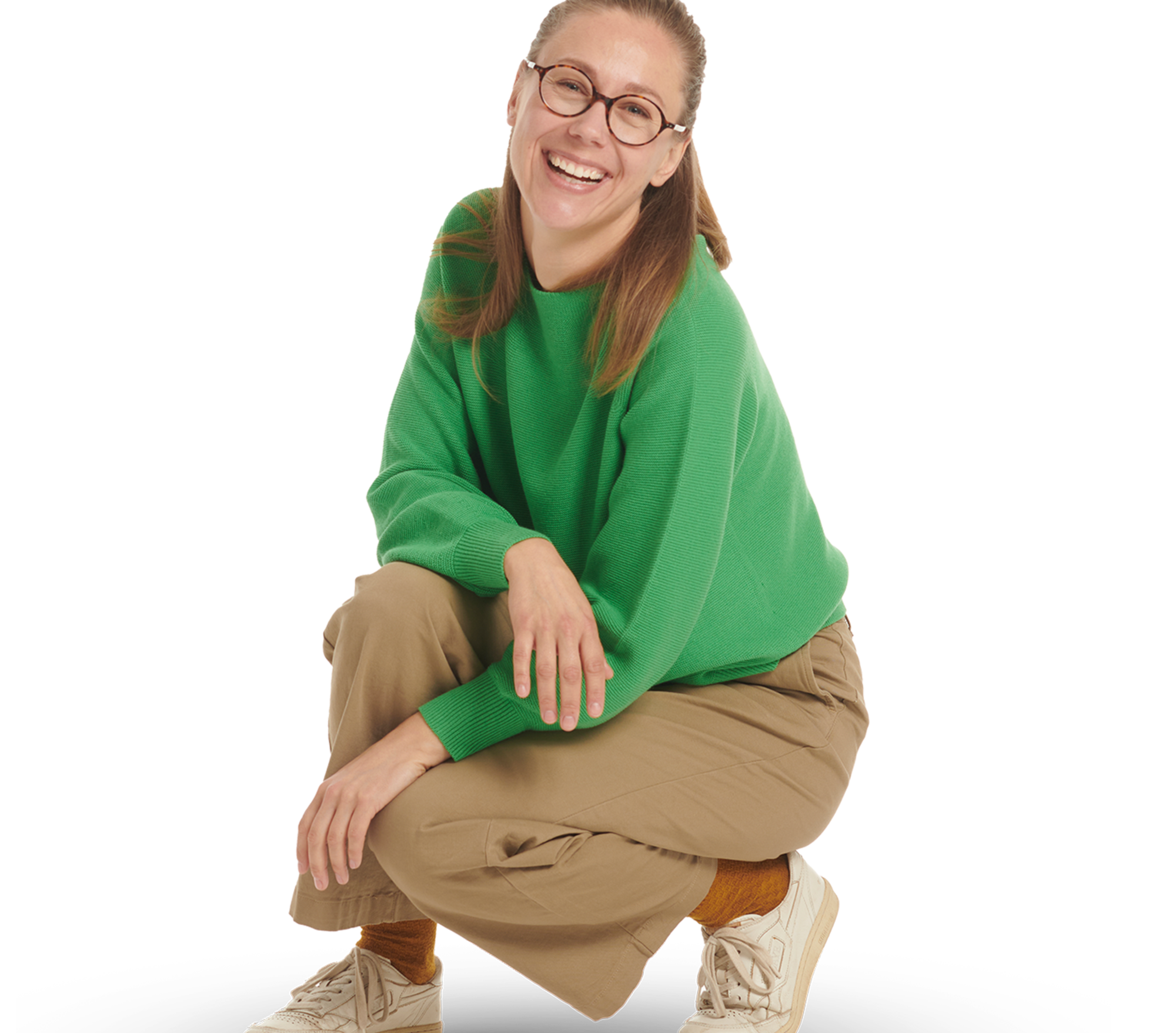 Eine junge Frau mit Brille in einem grünen Pullover in sitzender Haltung.