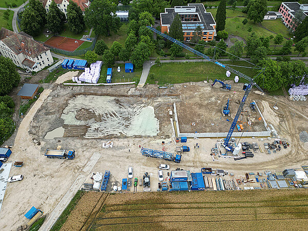 Drohnenaufnahme von einem Baufeld mit Kran und Baugrube.