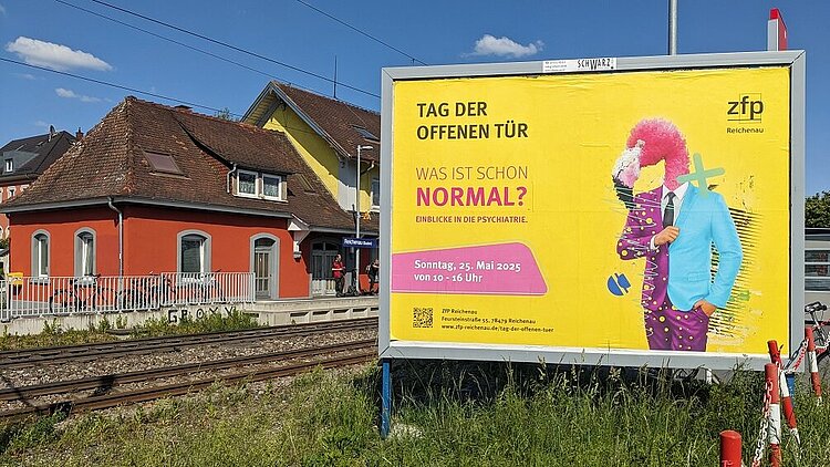 Das ZfP Reichenau wirbt mit einem großflächigen Plakat am Bahnhof Reichenau für seinen Tag der offenen Tür am Sonntag, 25. Mai 2025.
