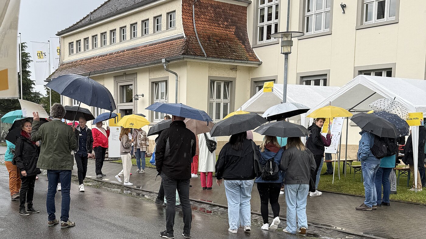Besucherinnen und Besucher sammeln sich am Tag der offenen Tür des ZfP Reichenau, weil sie an einer Führung teilnehmen möchten.