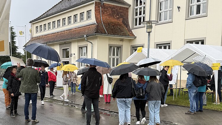 Besucherinnen und Besucher sammeln sich am Tag der offenen Tür des ZfP Reichenau, weil sie an einer Führung teilnehmen möchten.